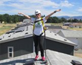 GRID solar installer on rooftop with solar panel, arms in the air
