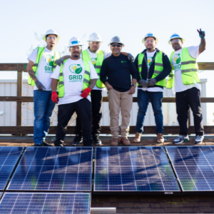 A group of trainees celebrate on a rooftop after installing solar panels