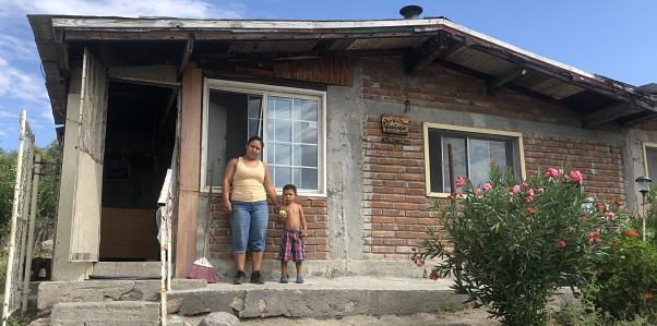 A Pai Pai mother and child stand in front of their house.