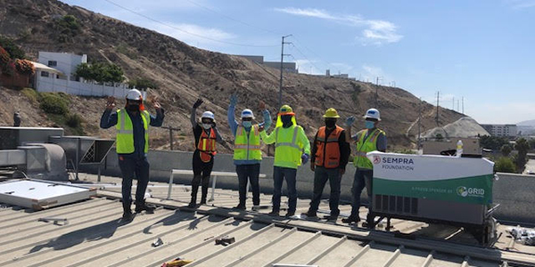 Construction crew on the roof at Pro Salud, with a Sempra banner