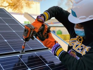 Trainee screws a solar panel in place